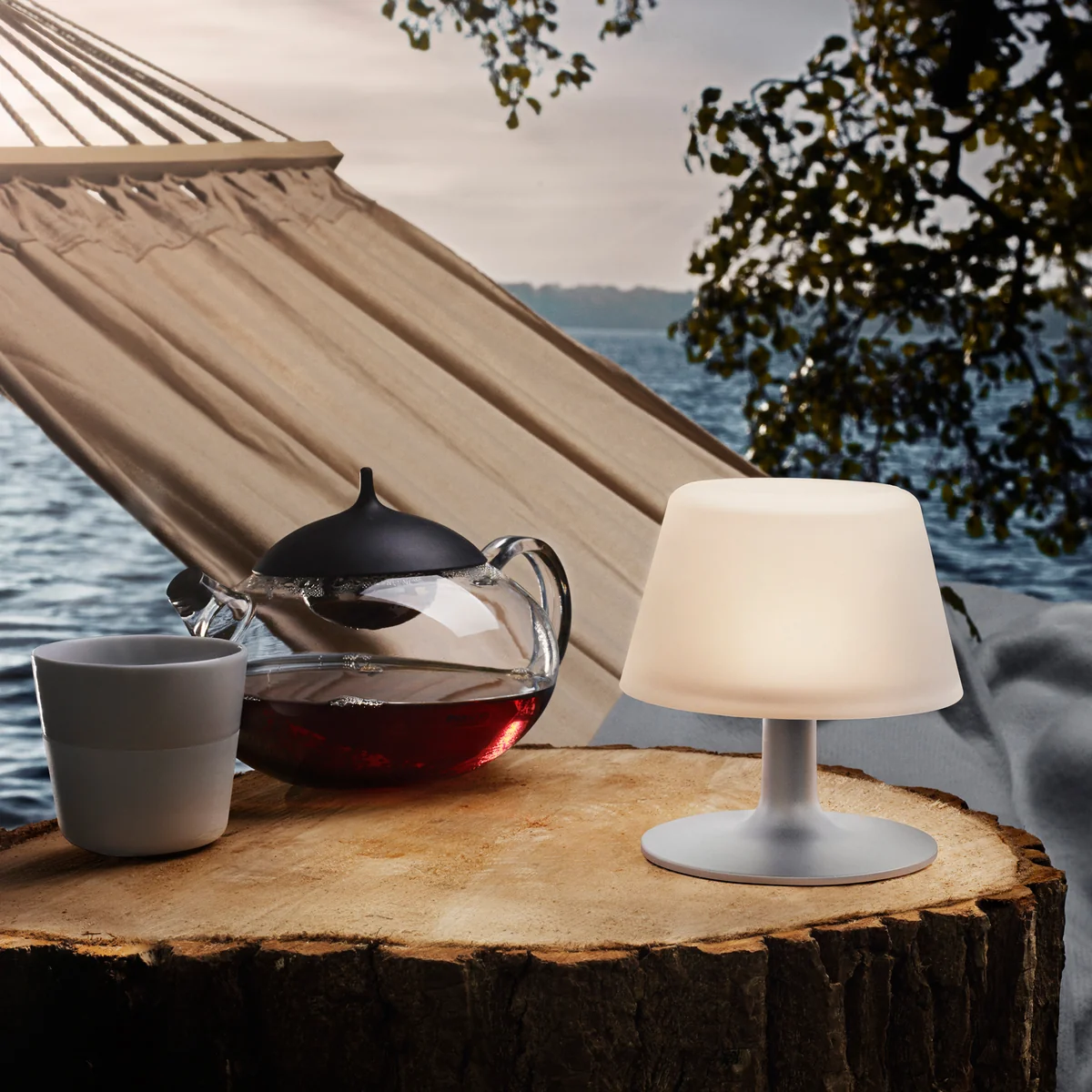 Die SunLight Tischleuchte von Eva Solo im Freien vor einer Hängematte Die SunLight Tischleuchte von Eva Solo im Freien vor einer Hängematte