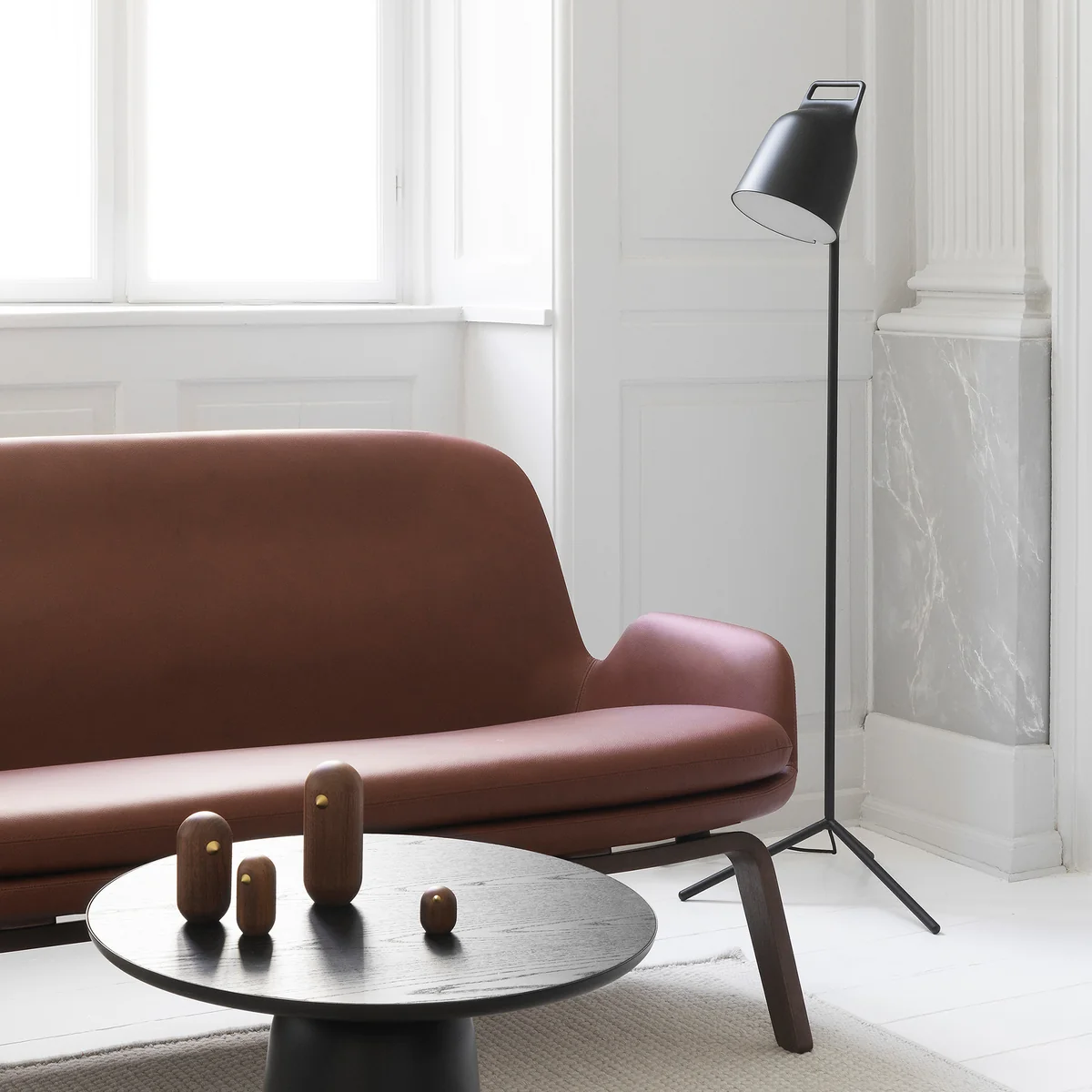 Die Stage LED-Stehleuchte von Normann Copenhagen neben einer braunen Leder-Couch