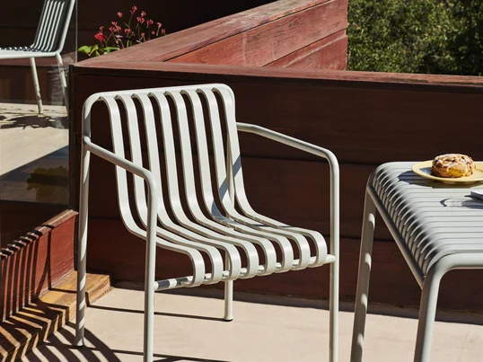 Der Palissade Dining Armchair von Hay in Hellgrau lädt mit seinen Armlehnen zum Sitzen und Verweilen im Außenbereich zum Beispiel auf der Dachterrasse ein.