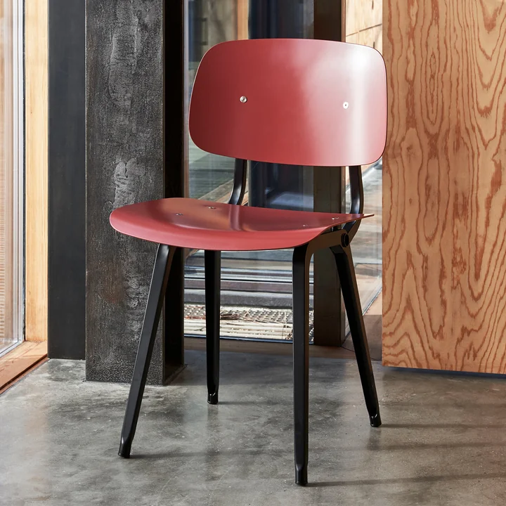 Der Revolt Chair, schwarz / plum red von HAY in einem Raum mit viel Holz und Stein