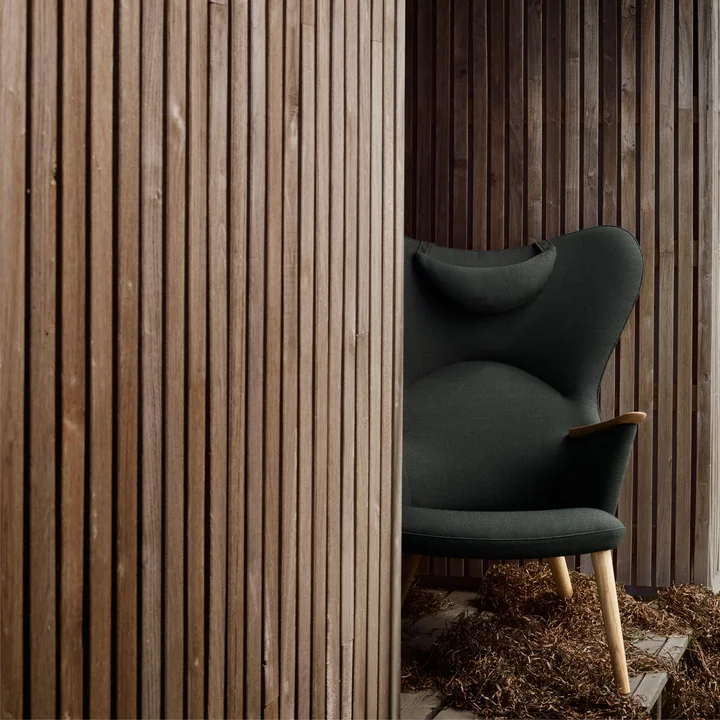 Der CH78 Mama Bear Lounge Chair von Carl Hansen zwischen rustikalen Holzwänden