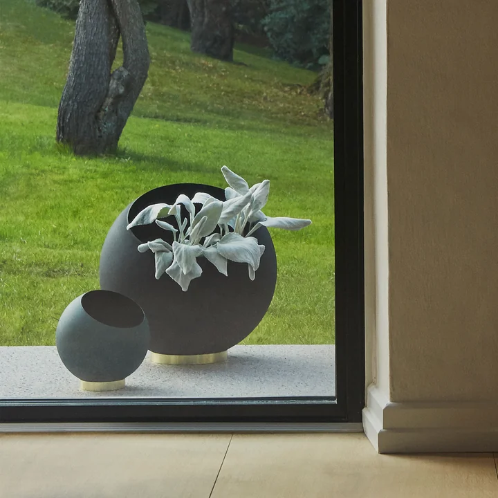 Der Globe Blumentopf von AYTM in seinen verschiedenen Größen hinter einem bodentiefen Fenster im Freien