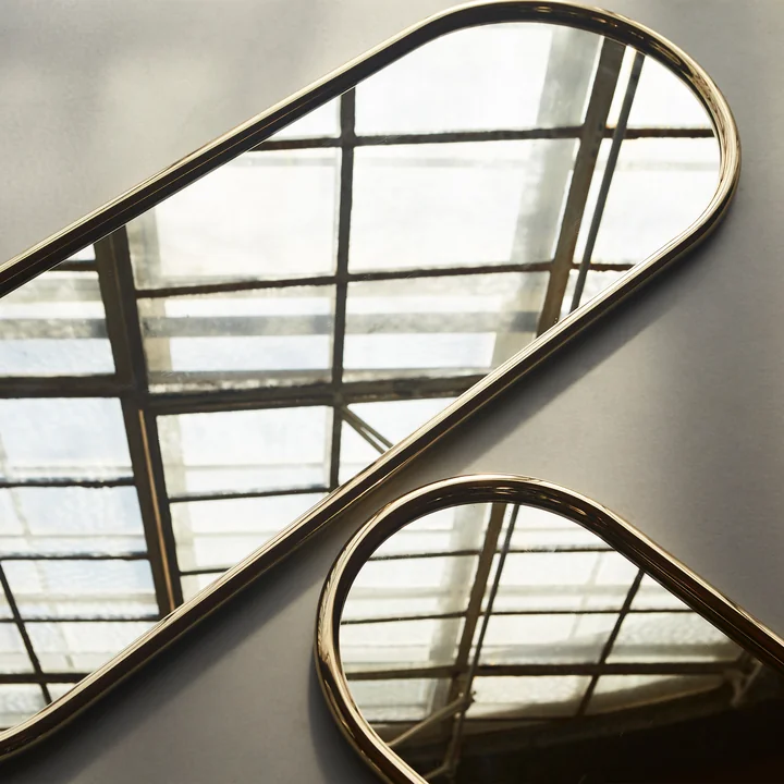 Der Angui Wandspiegel von AYTM auf dem Boden neben einem weiteren Wandspiegel