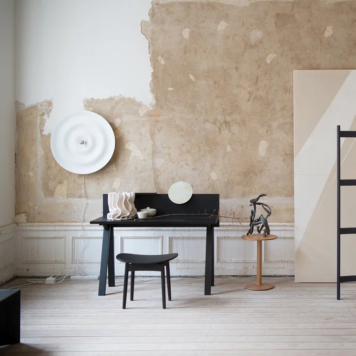 Die Alma Wand- und Deckenleuchte von Wästberg in weiß in einem hellen Atelier mit schwarzem Schreibtisch und Stuhl