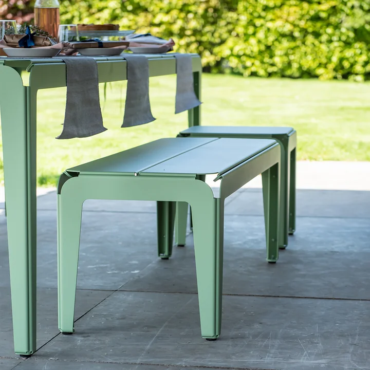 Die Bended Bench Bank mit dem Bended Tisch auf Steinplatten