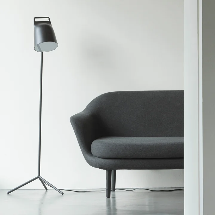 Die Stage LED-Stehleuchte von Normann Copenhagen neben einer grauen Couch